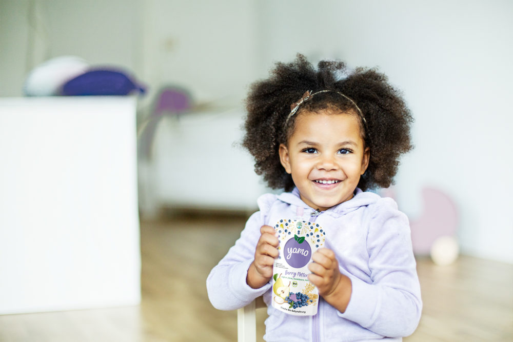 YAMO baby girl holding a YAMO product