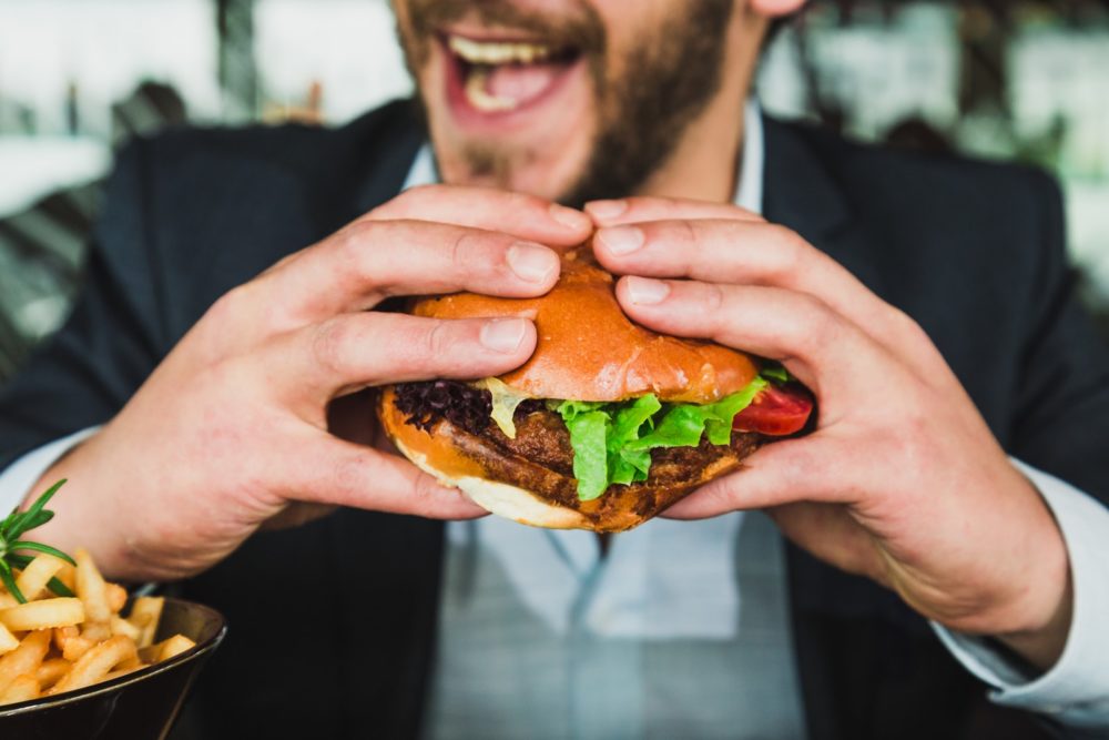 FlavorWiki - person holding burger bun with vegetables and meat